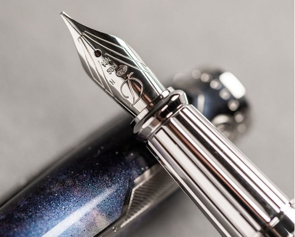 S.T. Dupont Space Odyssey Premium 410768L е впечатляваща лимитирана писалка от колекцията Line D Space Odyssey, произведена в серия от само 2001 броя. Масивният месингов корпус е покрит с дълбок син естествен лак с блестящи частици, напомнящи звездно небе, и е завършен с елегантни паладиеви детайли. В сърцето на пишещия инструмент стои 14-каратово златно перо с размер M, създадено за плавно и прецизно писане. С размери 15 × 1,5 cm и тегло 65 g, Space Odyssey Premium има солидно присъствие и подчертан колекционерски характер. Създадена за хора, които гледат отвъд познатото, 410768L превръща необятността на Космоса в изключителен френски пишещ инструмент.